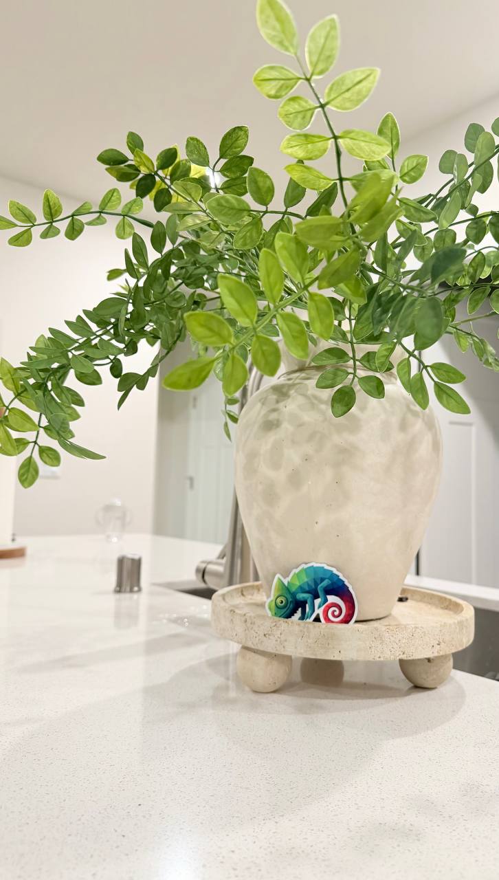 Chameleon sticker by a white vase with greenery