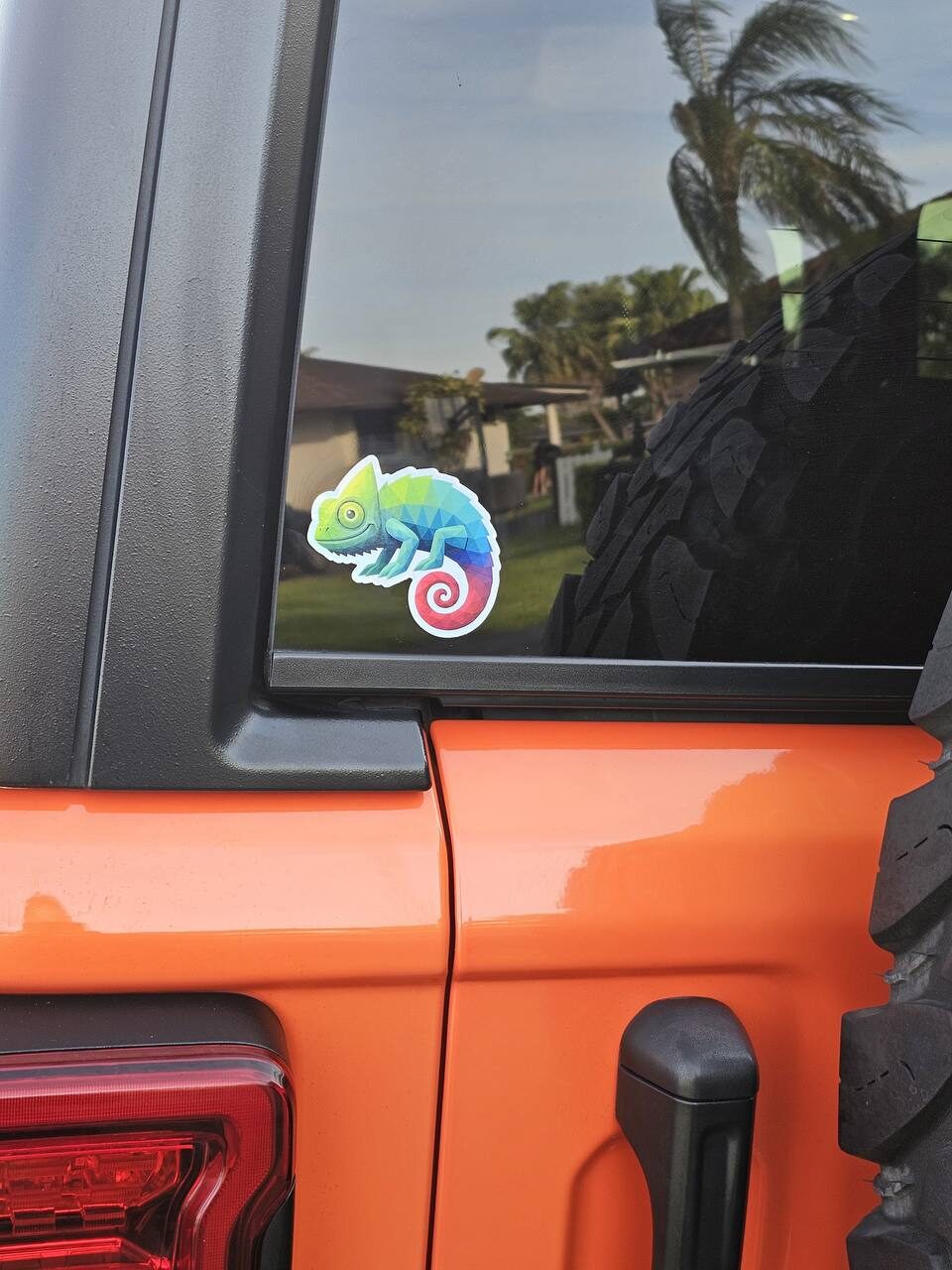 Chameleon sticker on the rear side window of an orange Jeep