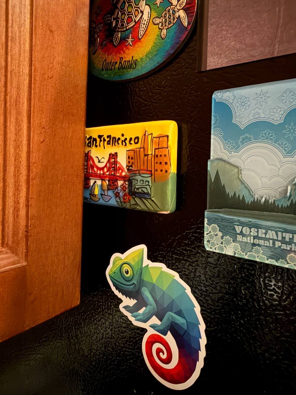 Chameleon sticker on a refrigerator among travel magnets